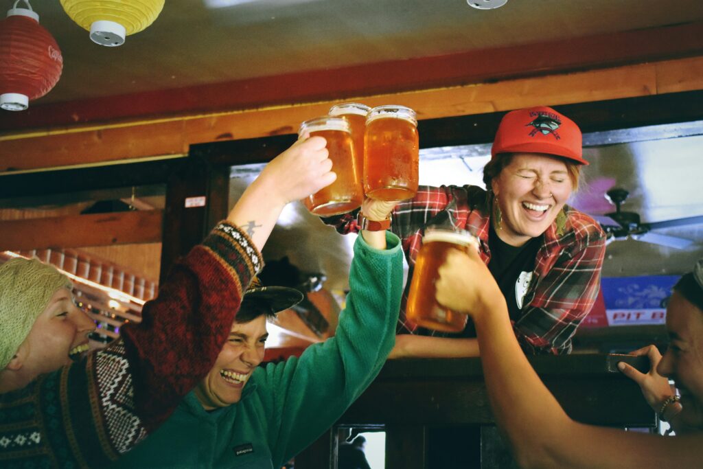 Auf dem Bild sind 4 Frauen in einer Bar, die deren Bier anstoßen