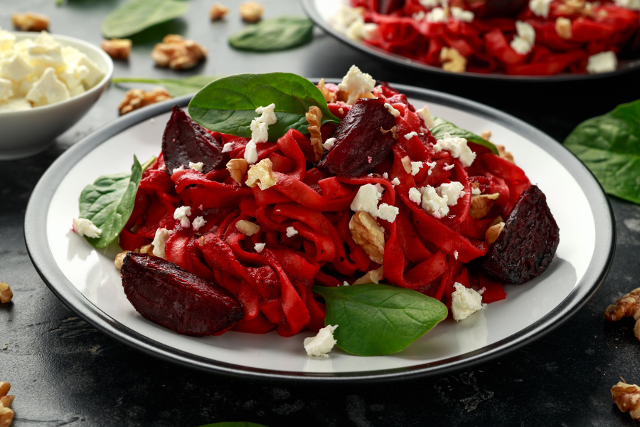 Tagliatelle mit Sauce aus roter Bete, angerichtet auf einem Teller mit Walnüssen und Feta, Herbstrezept