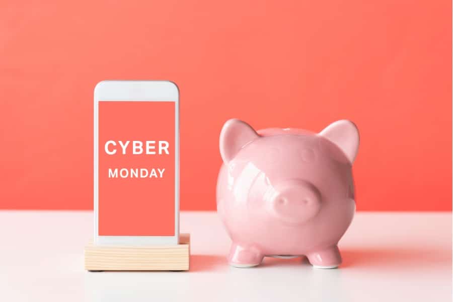 Auf diesem Bild sieht man auf der rechten Seite ein Sparschwein und auf der linken Seite ein Handy mit der Beschriftung „CYBER MONDAY“