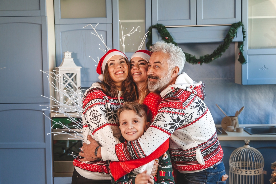 Familie die sich umarmt in Weihnachtsklamotten