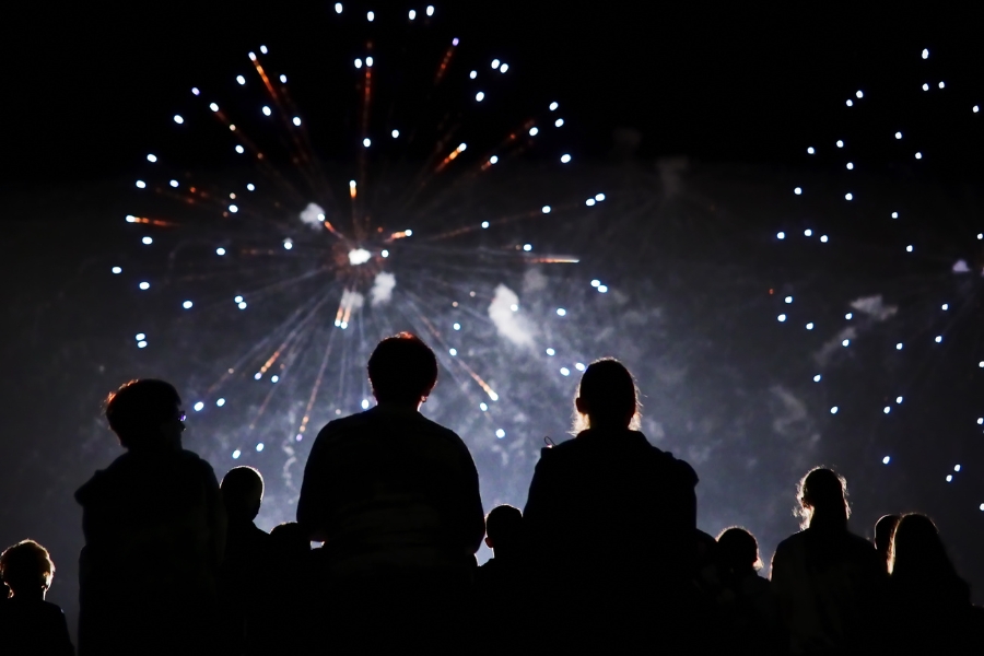 ein Feuerwerk am Nachthimmel, Konturen von Menschen im Vordergrund