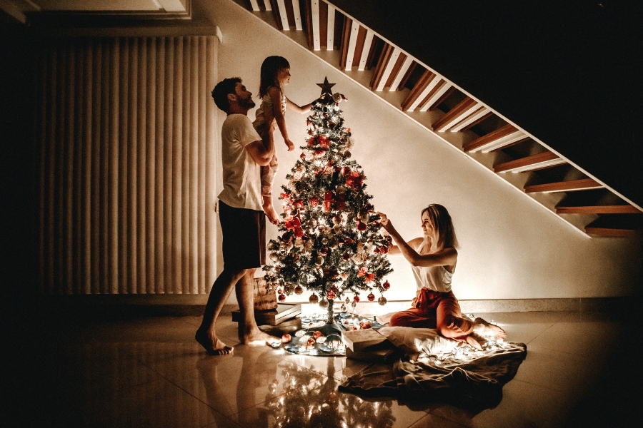 In der Dunkelheit schmückt eine kleine Familie einen schon leuchtenden Christbaum