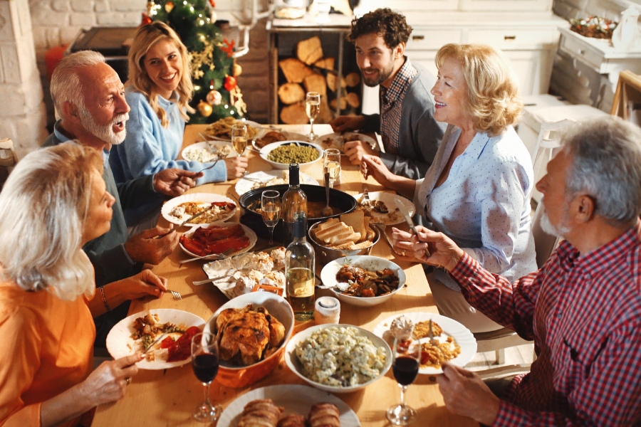 Familie sitzt am reich gedeckten Tisch zu Weihnachten